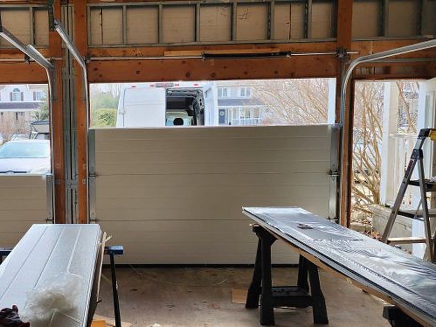 New insulated garage door part way through installation, the remaining sections staged on trestles inside the garage